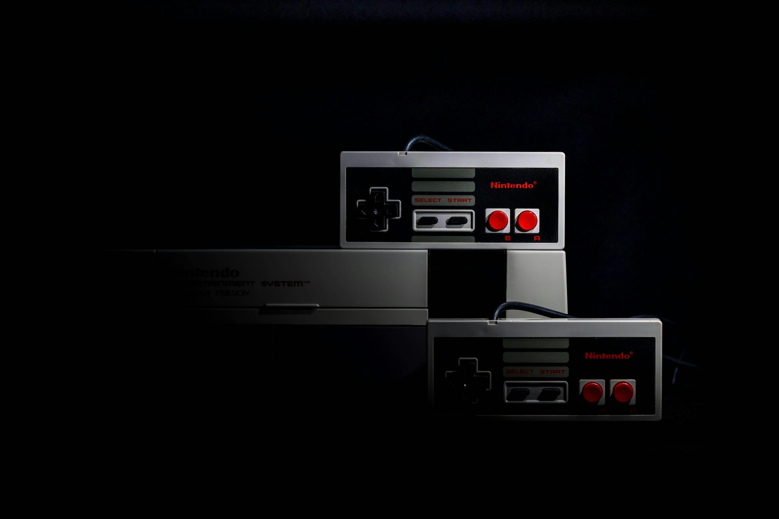 Retro gaming controllers from the Nintendo Entertainment System in low-key lighting, evoking nostalgia.